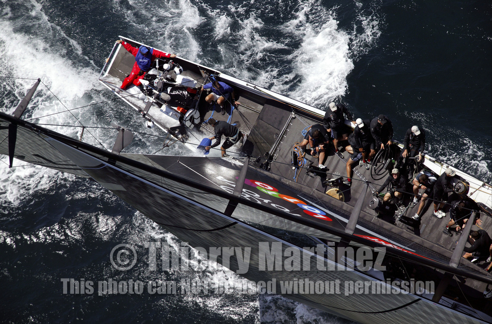 03_0170D ©Th.Martinez - Auckland (NZ) . America's Cup 2003. 15th February 2003. Day 1..Alinghi (SUI 64) vs Team NZ (NZL 82) .NZL 82 in first minutes of Race 1 before retiring on damage. Alinghi 1- Team NZ 0 .Matt Mitchell (Team NZ midbowman) bailing water out of NZL 82. .