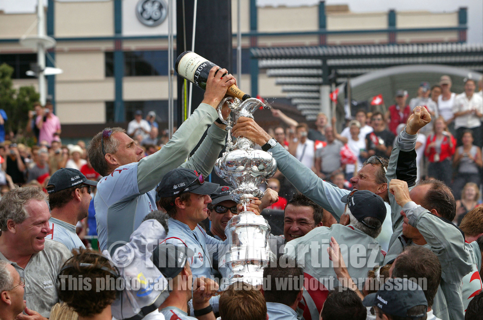 03_1429D © Th.Martinez . Auckland   New Zealand. 2nd March 2003 America's Cup 2003. Day 5, Alinghi (SUI64) vs Team New Zealand (NZL82). .Alinghi winner of the 31st America's Cup (5-0). Docking ceremony, presentation of the America's Cup in the Viaduct Bassin. Grinder Jan Neergaard, .poring MOET champagne in the Cup.
